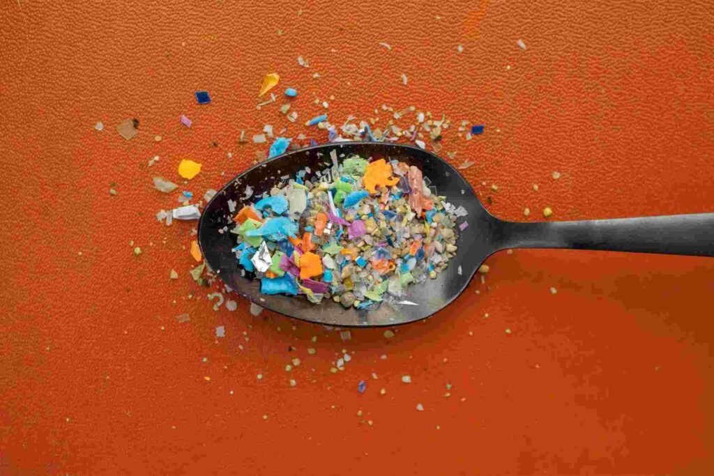 dark metal spoon holding a colorful plastic pieces